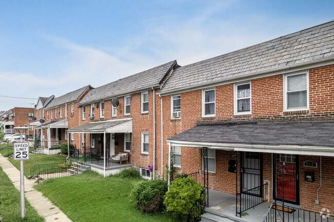 Find traditional row homes featuring red-brick and stone facades and short roofed porches.