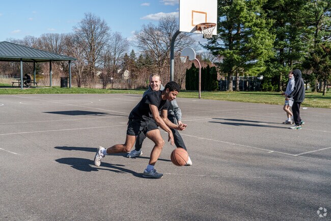 Teenagers in Midtown Manor take advantage of the warm weather with a basketball game.