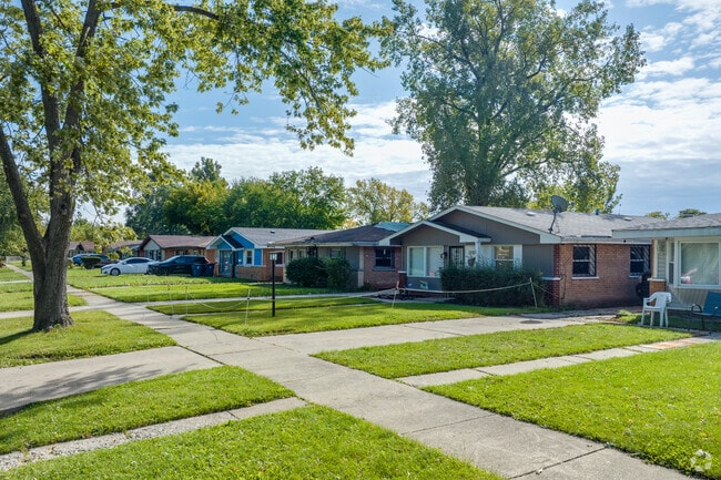Row of bungalow style homes with large front lawns and tree lined street in Ford Heights, IL.