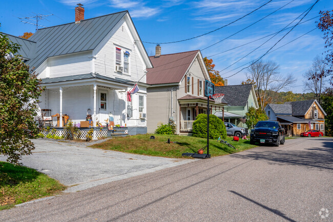 A row of colonial style homes in East Barre are close together with small yards and porches.