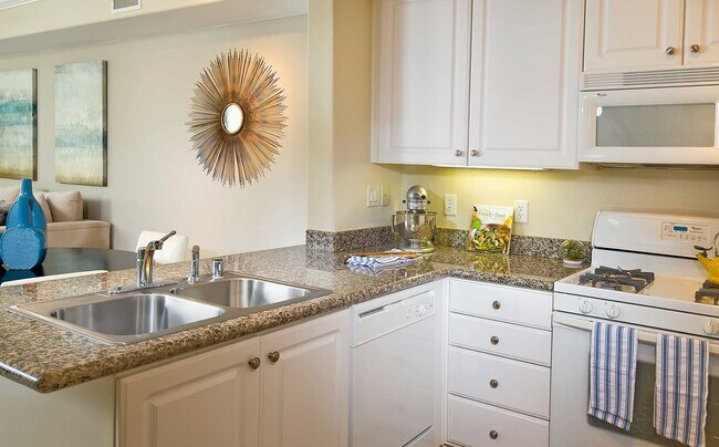 Classic Package I kitchen with white appliances, beige speckled granite countertop, white cabinetry, and hard surface flooring