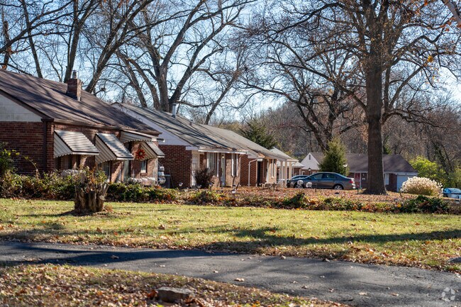 Mature trees grow around brick ranch styles in Ferguson.