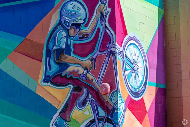 A colorful mural of a BMX biker doing a trick can be on the wall in Downtown Oswego.
