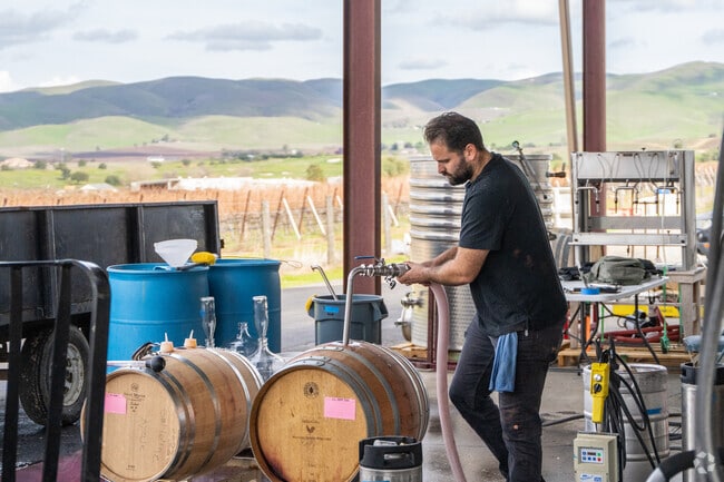 A Winemaker at Steve Winery is busy tending to their wine barrels.