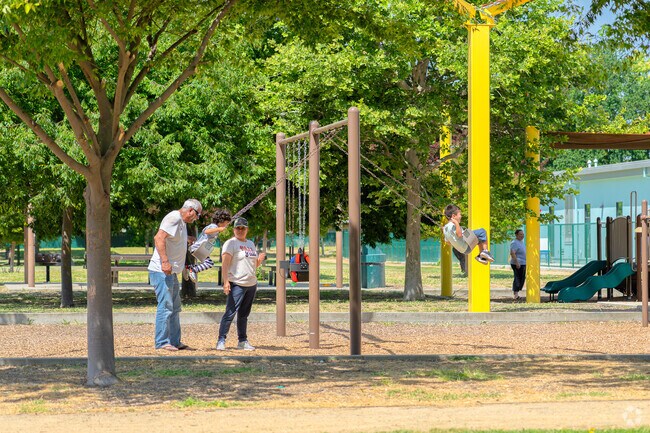 A grandpa pushes his grandchildren on the swings at Westfield Park.