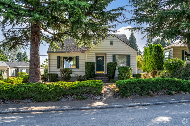 Evergreen trees cast shade on this cozy cottage in the quiet neighborhood of Lowell.