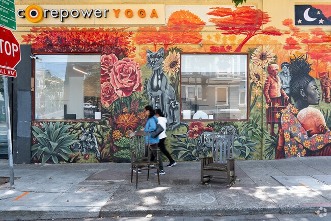 Two women pass by 'Domestic Seating' art installation at Duboce Ave and Church St MUNI station.