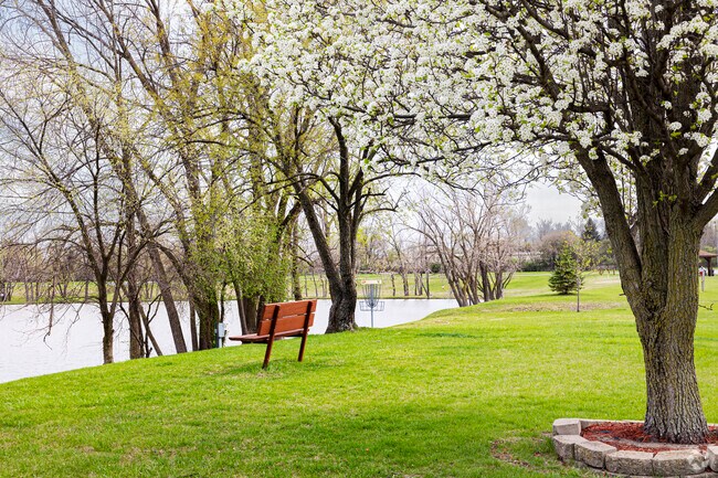 Turkey Creek nature lovers take a beat on a shady bench by the calm water of Hidden Lake Park.
