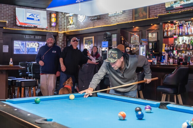 A local at V&E Club in Downtown Livermore prepares to drain a shot while patrons look on.