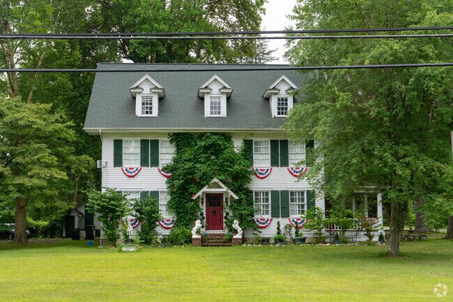 Historic-style three-story home in Elwood, NJ, featuring patriotic decor and lush landscaping.