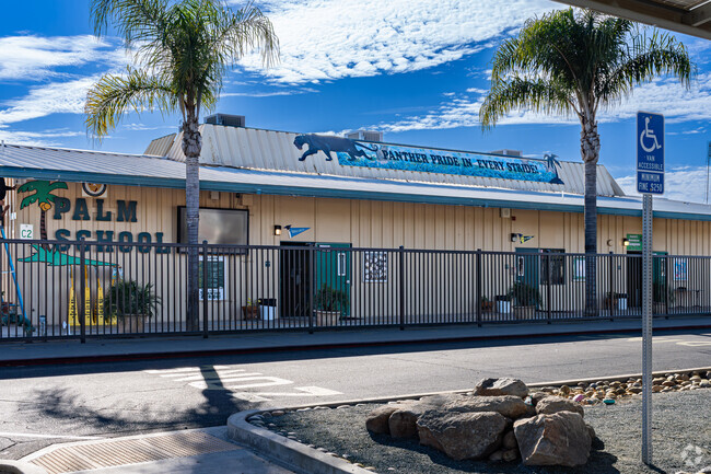 The front of Palm Elementary School is shaded by two large palm trees.
