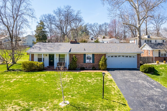 A brick ranch style home sits in a large yard