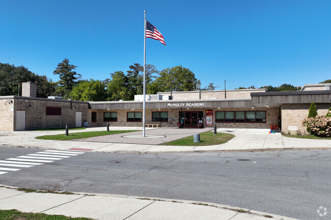 A flag stands in front of Raphael J Mcnulty Academy greeting you.