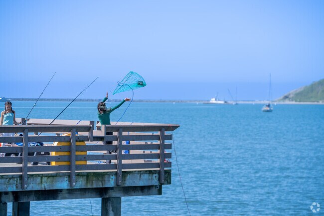 A young angler in El Granada casts her crab net into the sea, hopeful for a catch.