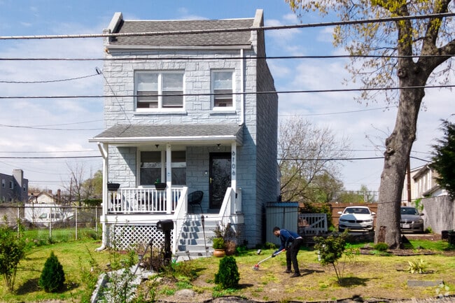 A man tends to the lawn next to a detached row home.