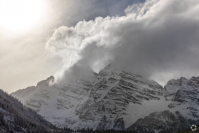 Dramatic clouds swirl around Maroon Bells, enhancing the majesty of the snow-capped peaks in Aspen.