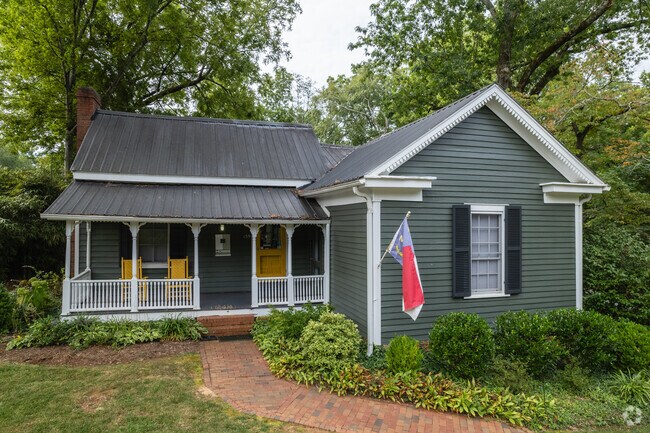 A turquoise-colored bungalow with a North Carolina flag in the front.