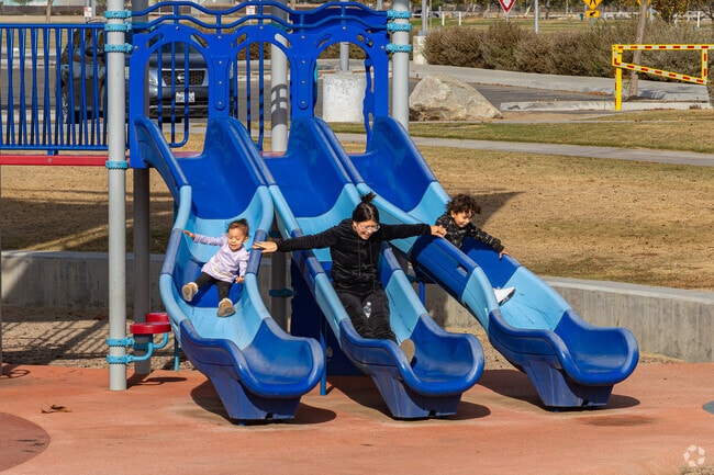 A Laurelglen mother joins her kids on a park slide at Sports Village Soccer Complex.