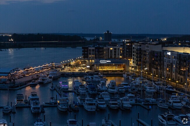 Upper Downtown is lit up at night with outdoor dining and boats on the marina.