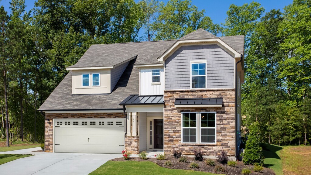 Single family home featuring light color stone watertable, front porch, and a white front two-car garage.
