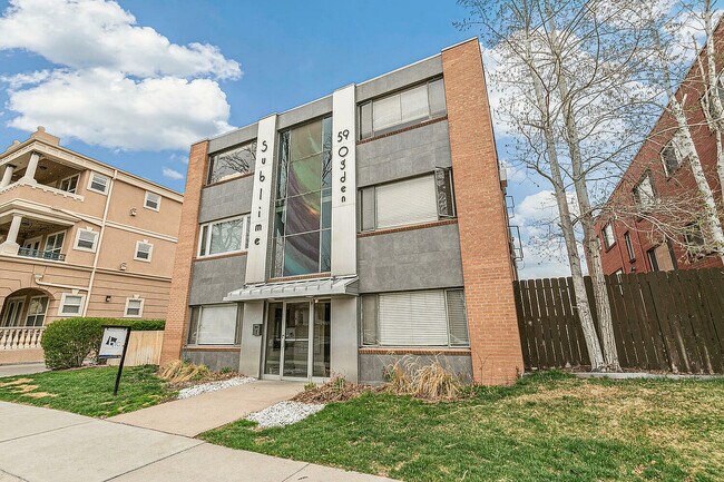 Charming modern apartment building with stylish facade, surrounded by lush greenery and clear blue skies.