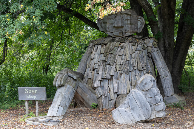 Large wooden trolls sleep under the trees at the Lincoln Memorial Garden.