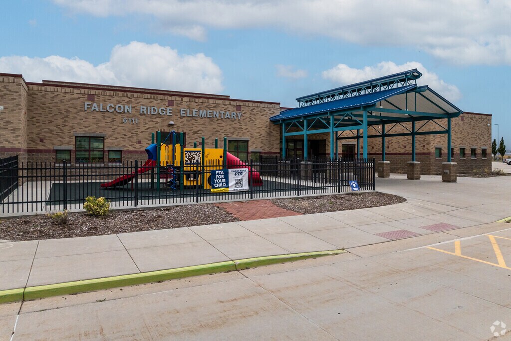 A blue and teal metal awning covers the entryway at Falcon Ridge Elementary School.