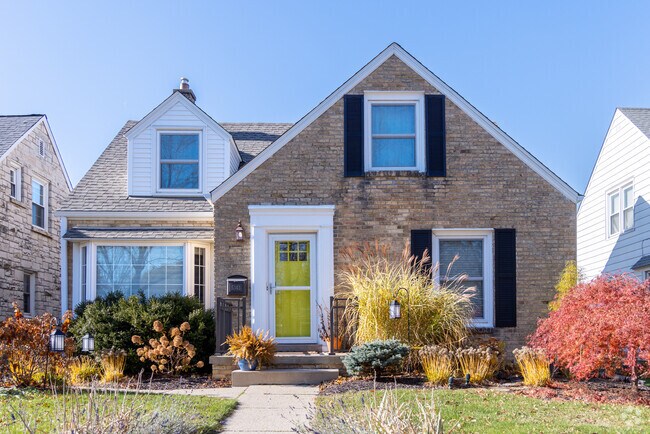 A Cape Cod home in Parkway features a vibrant yellow door and a well-landscaped yard.