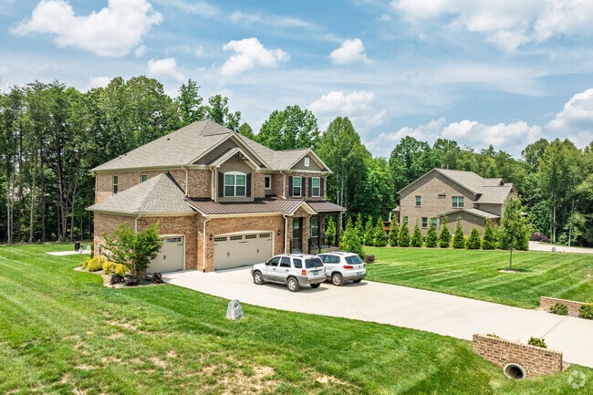 Tall trees frame a stately brick home that anchors a quiet street in Browns Summit.
