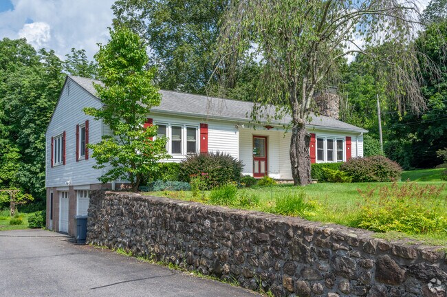 A raised ranch-style home with red shutters and a stone wall adds charm to Southeast.