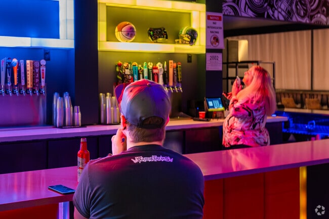 A patron enjoys a beer at the colorful bar in High Caliber Karting and Entertainment in Okemos.
