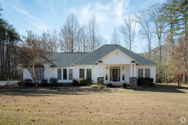 A classic white Tudor Revival home stands proudly amid the scenic streets of Holly Springs.