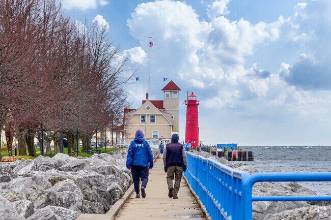People walk towards the Muskegon South Pierhead Lighthouse in Beachwood-Bluffton.