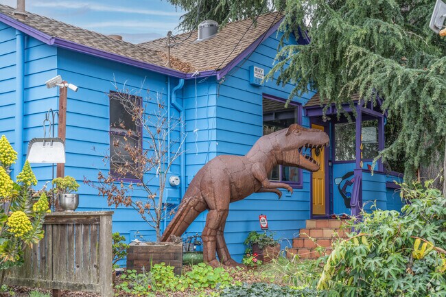 A sculpture of a T-Rex sits in front of this brightly colored bungalow in South Berkeley.