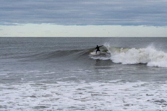A surfer catches a waves at the beach in Hampton.