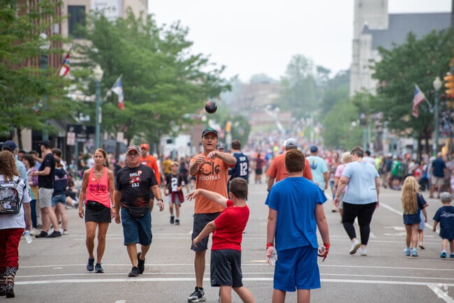 Families play catch with a football while they wait for the Canton Repository Grand Parade.