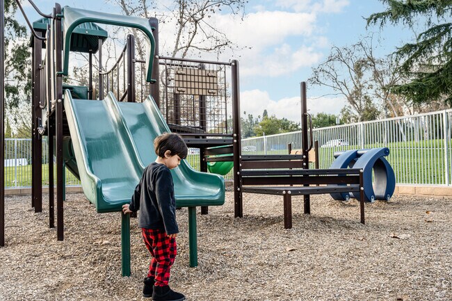 A child playing by the dual slide at the fenced in playground at Hacienda Park La Habra Heights.