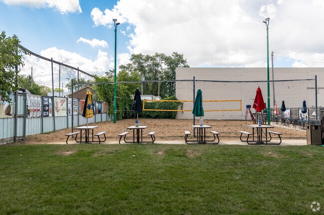 A row of picnic tables are placed perfectly to watch a game of beach volleyball at Coach’s Pub.