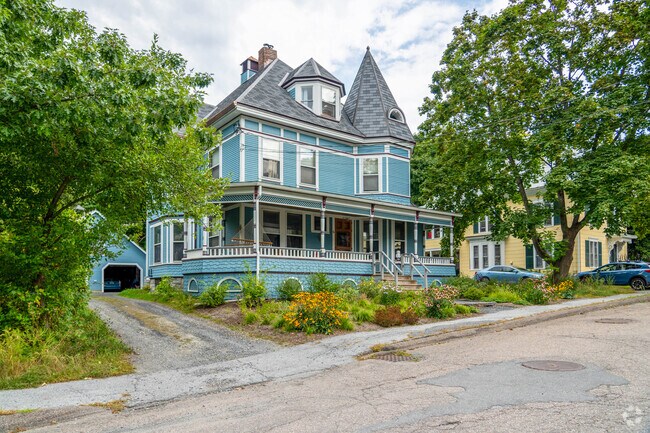 A light blue Victorian home in College Hills has a wraparound porch and detached two-car garage.