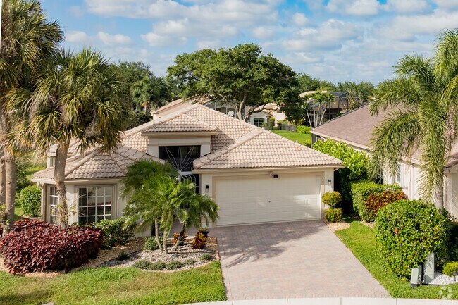 Mediterranean ranch home framed with lush landscaping in Valencia Isles.