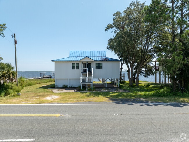 A stilted waterfront house with a blue roof stands ready for storms on Florida’s Forgotten Coast.