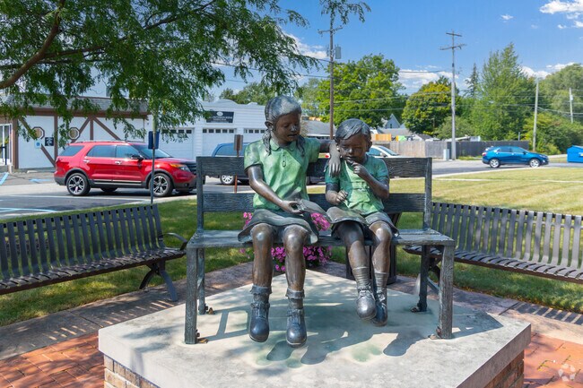 A statue of kids reading stands in front of Ossian Library.