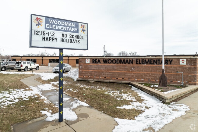 There is a sign for Woodman Elementary School near the entry.
