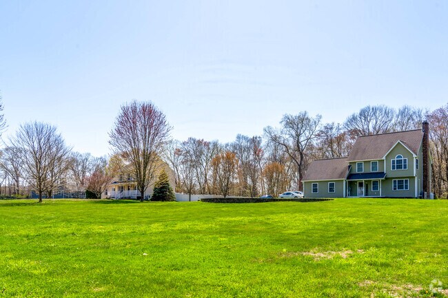 A row of three homes in Scotland sits atop large lots with expansive yards spaced apart.