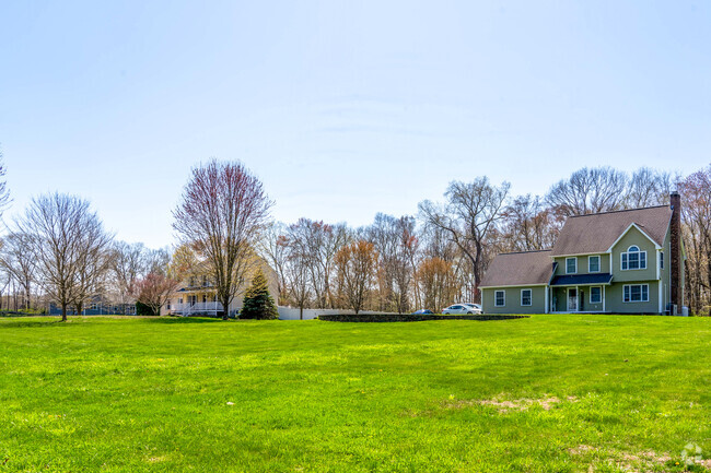 A row of three homes in Scotland sit atop large lots with expansive yards and spaced out from eachother.