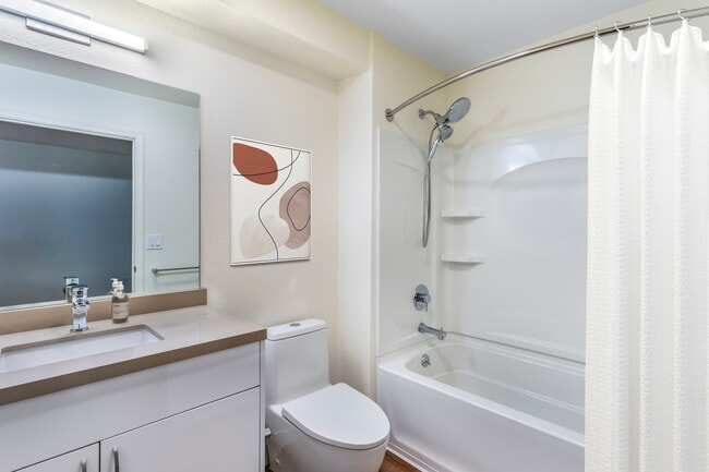 Renovated Package II bath with beige quartz countertops, white cabinetry, and hard surface flooring