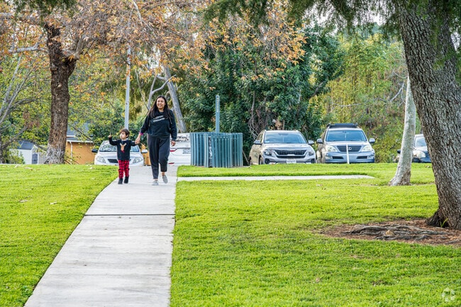 A mom and child walk to the fenced-in playground at Hacienda Park in La Habra Heights.