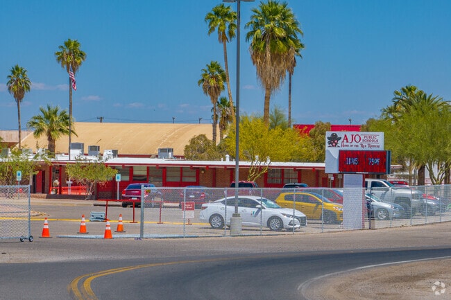 The entrance to Ajo Unified School District's campus is marked by palm trees and red signage, welcoming families to the connected school site.
