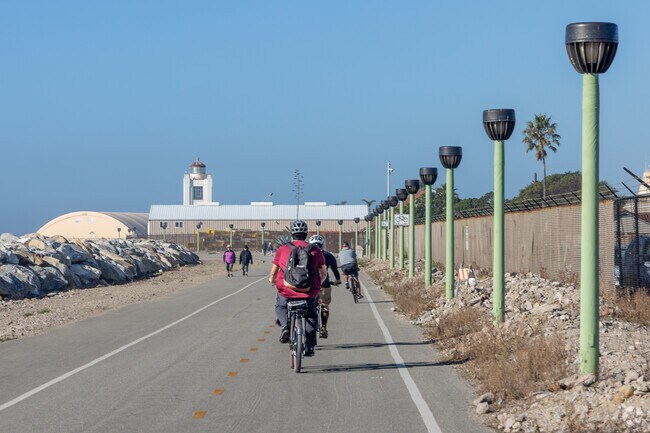 Bikers and walkers can be seen on the promenade walkway leading to the Port Hueneme Lighthouse.