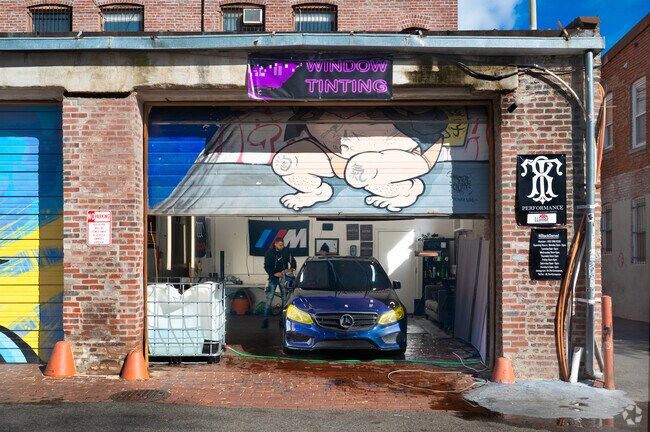 A car detailing shop in an alleyway in the Truxton Circle neighborhood shows off one of many public art pieces.